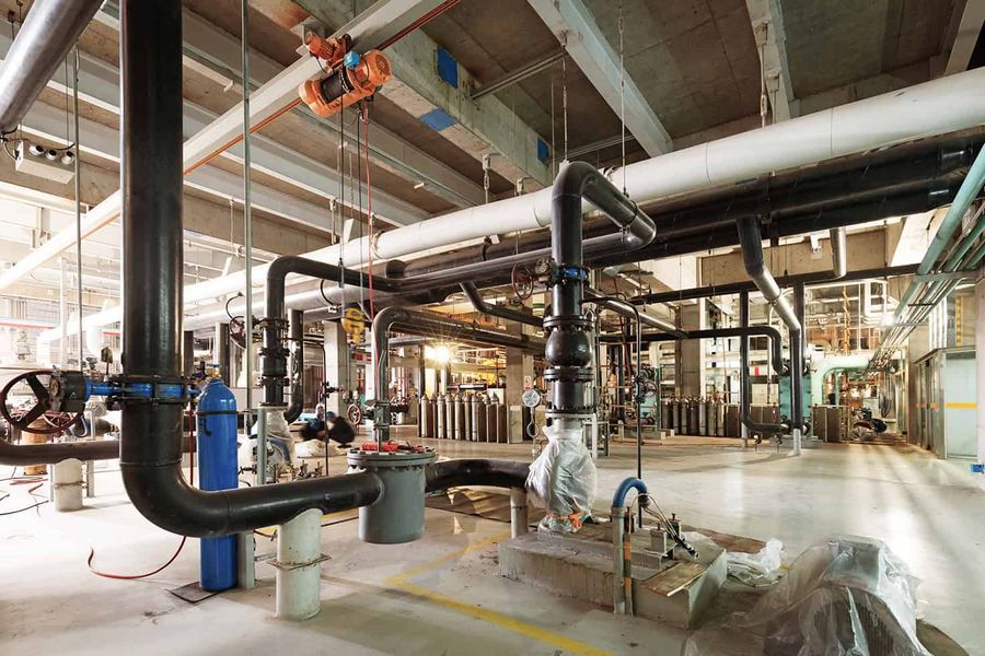 Commercial mechanical room with large-diameter piping, valves, and overhead hoist