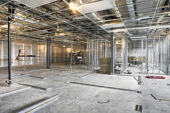 Commercial tenant space under build-out with metal framing and overhead utilities